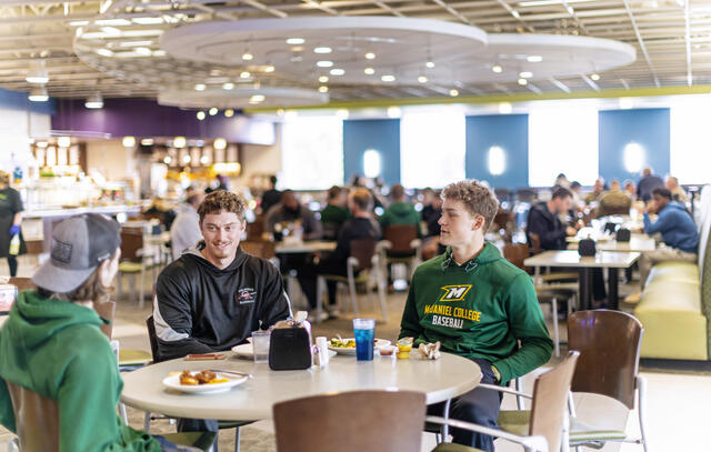 Students sit at table in dining hall