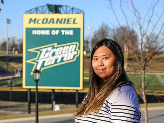 Brianna Myung standing on campus with the McDaniel Home of the Green Terror sign in the background.