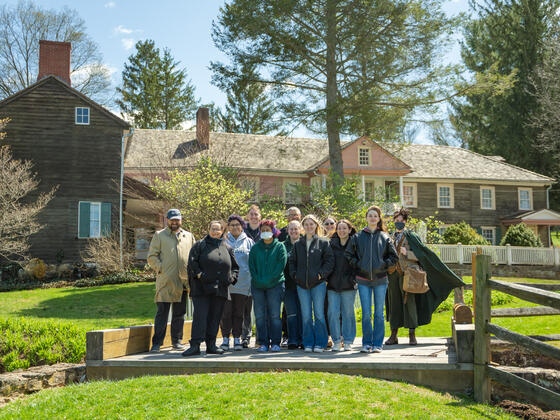 Group photo of students and a professor standing outside of Union Mills Homestead house.