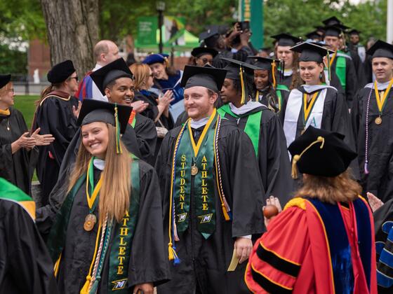 Students in graduation regalia walk in rows