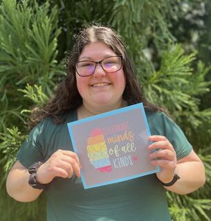 A female young adult holds up a motivational sign