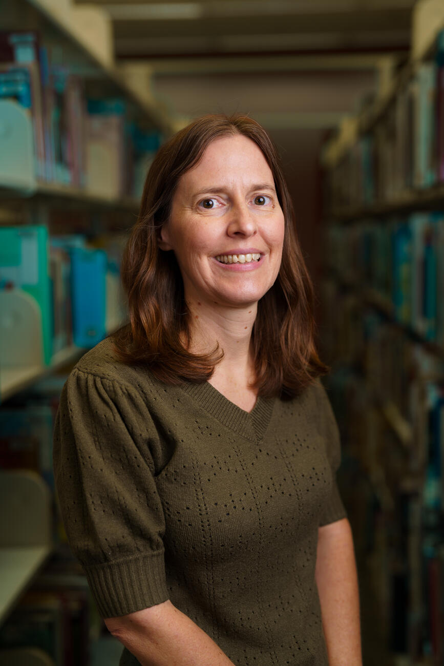 Headshot of lecturer Lisa Buckler standing in a library.