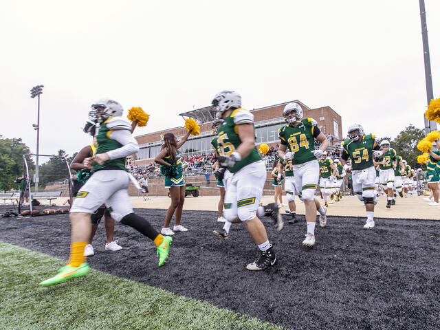 Football players running onto the football field.