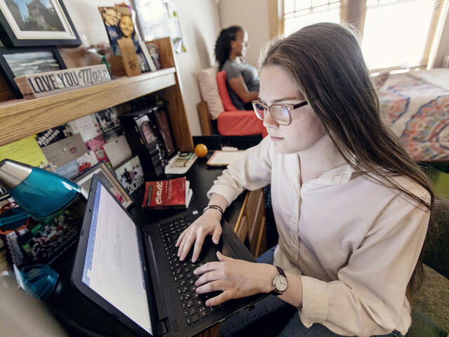 Students on computers in residence hall room.