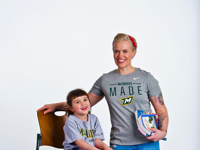 Brittany Sears holding books standing next to daughter.