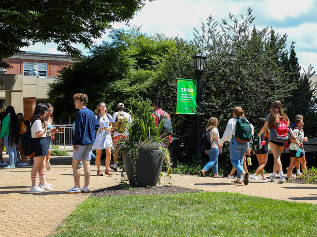 students walk on campus in front of Roj Student Center