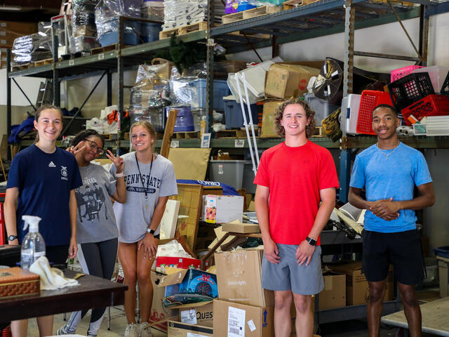 Five students pose in the Habitat for Humanity ReStore warehouse.