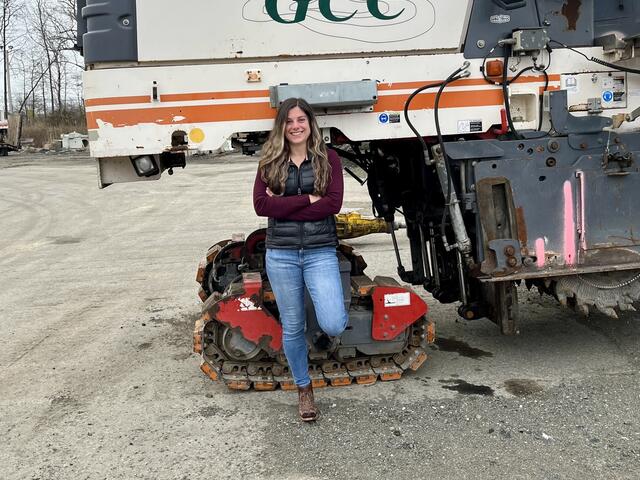 Photo of alum Perri Freeman standing in front of construction machinery.