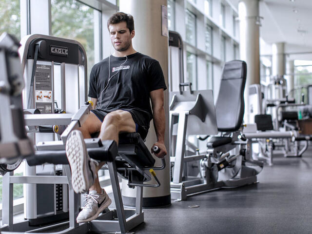 Photo of a student using a weightlifting machine in Merritt Fitness Center.