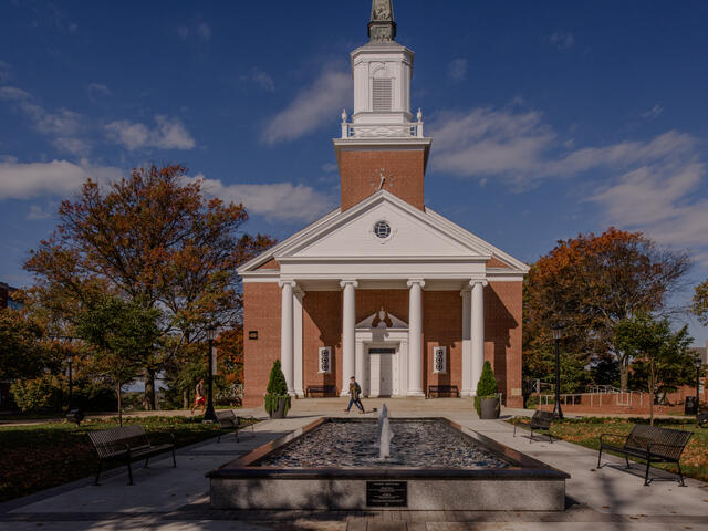 Large chapel with white steeple and white columns with a fountain in the foreground