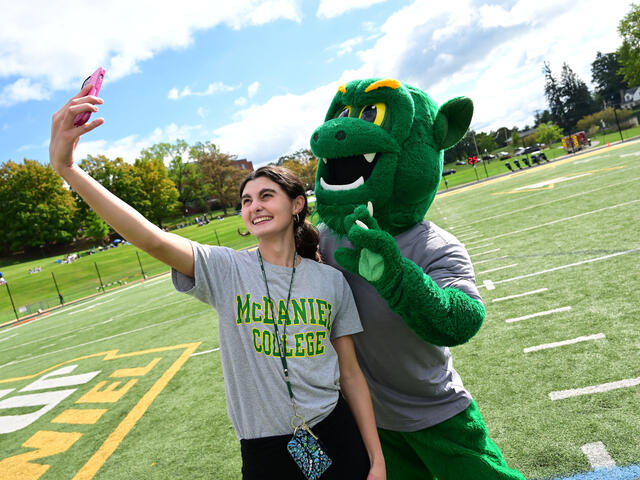 A student takes a selfie with the Green Terror mascot.