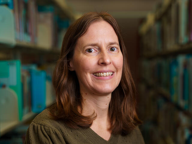 Headshot of lecturer Lisa Buckler standing in a library.