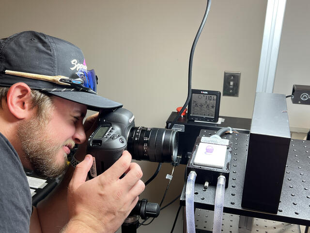 student looks through a camera at equipment