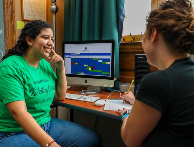 Two students in talking in front of a computer in the Writing Center.