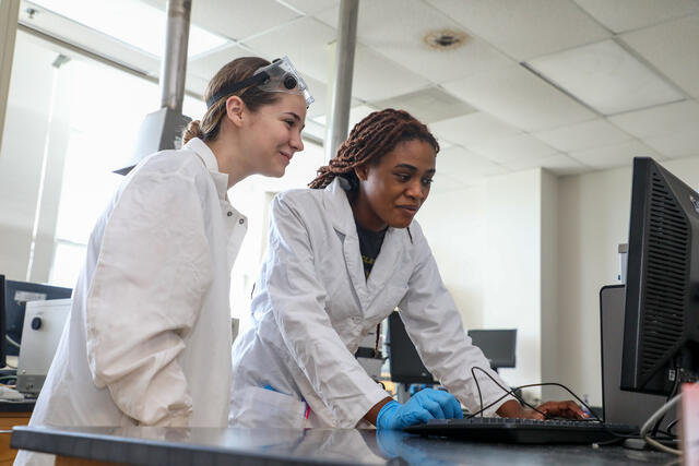 Two students in a lab look at a computer together.