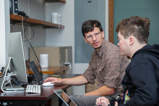 Professor Paul Muhlhauser advises a student in class while at a computer.