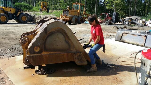 Alum Perri Freeman working on paving equipment outdoors.