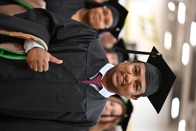 Student in regalia with thumbs up