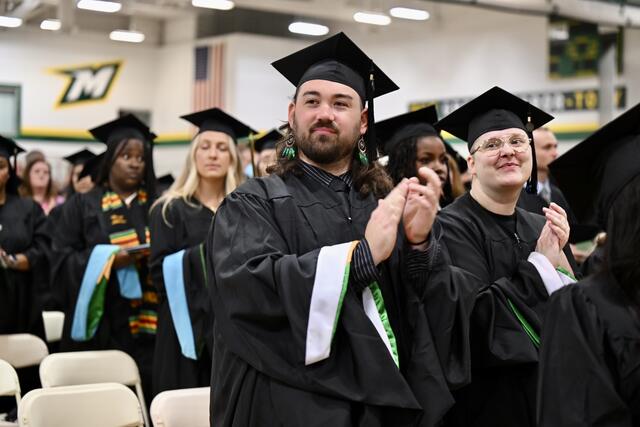 Students in commencement regalia clap