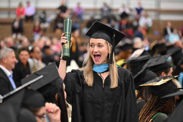 Student holds up diploma during commencement ceremony