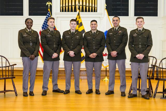 A group of six ROTC cadets poses together on stage at their commissioning ceremony.