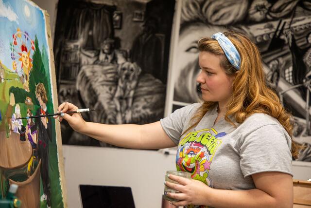 A student paints on a canvas. 