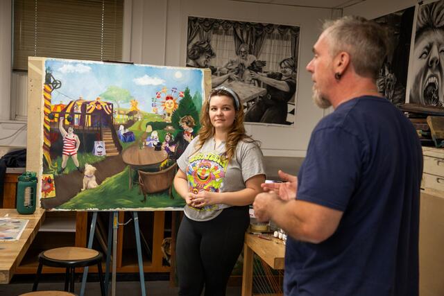 Professor of Art Steven Pearson speaks with a student in front of an easel in the Art Studio.