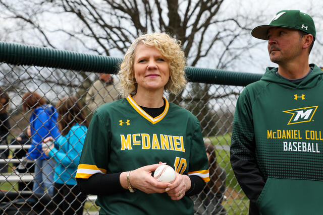 McDaniel President Julia Jasken wears a McDaniel baseball jersey while holding a baseball.