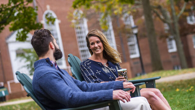 Grad students sitting in outdoor chairs on campus.