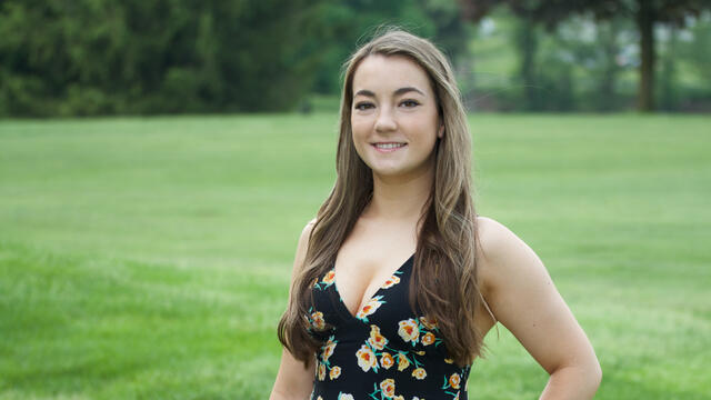 Alumna Caitlin Eversmier '18 in a grassy field.