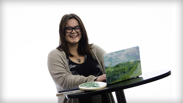 Kaylor Stroot poses with an open laptop on a table.