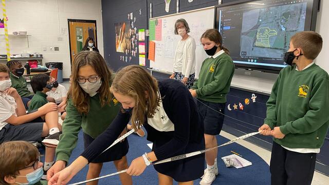 Clare Hoerl in the classroom with her students while they learn to use measuring tapes.