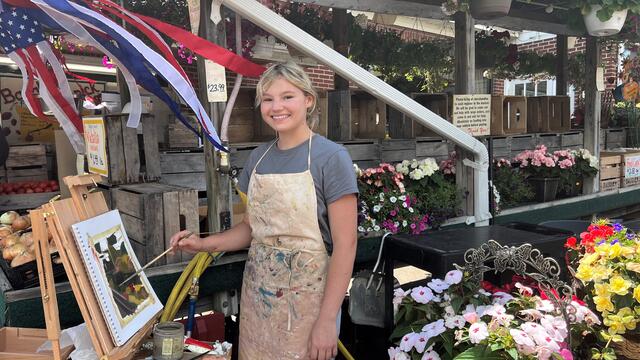 Student Mandy Smith painting on an easel at Baugher's local market stand.