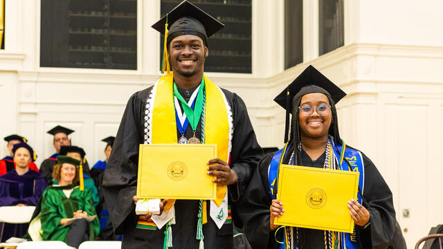 students in graduation regalia pose with awards