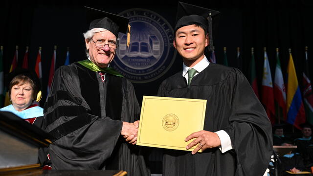 Student in graduation regalia presented an award